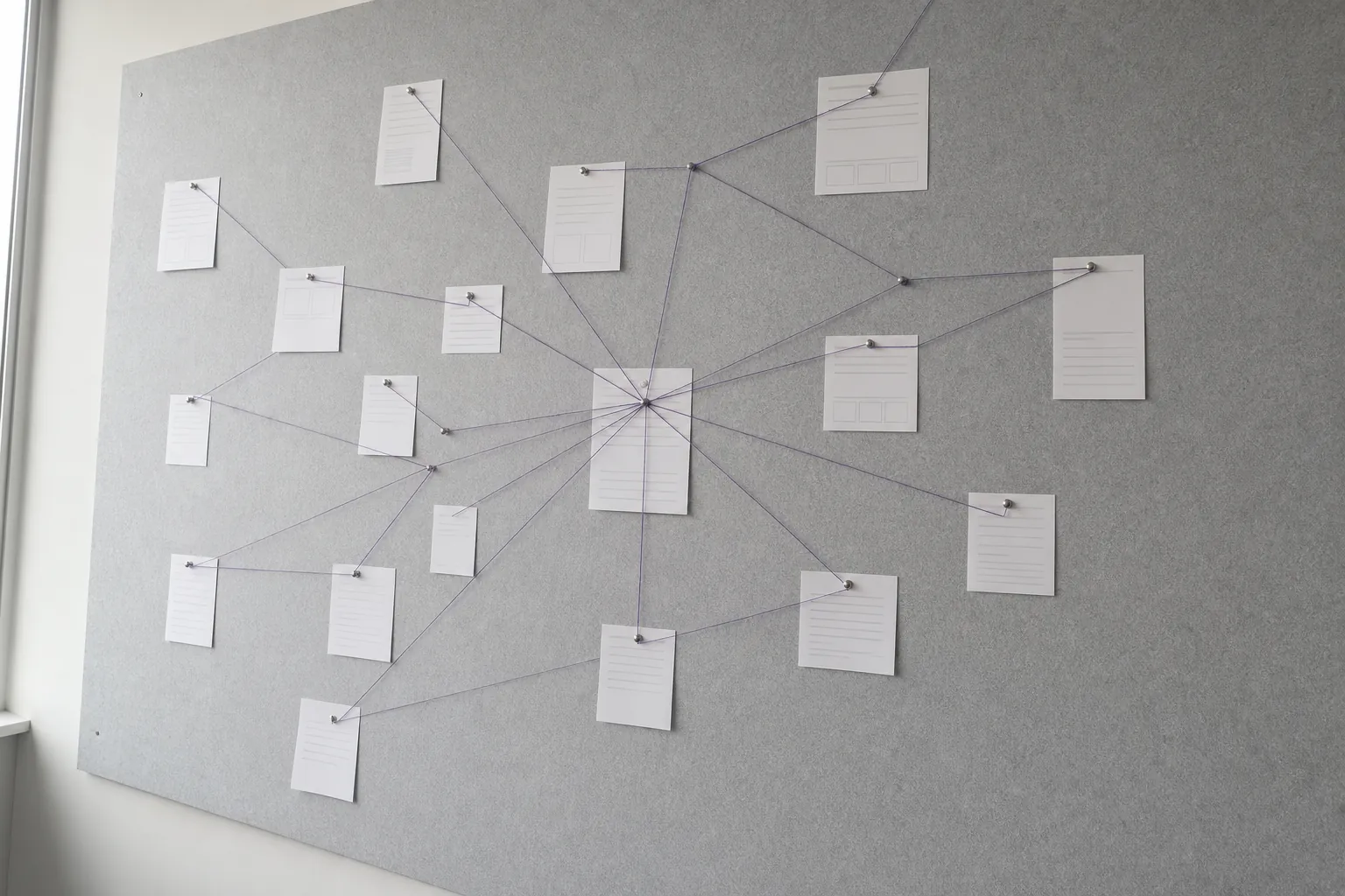 Pages pinned to a board, connected by thread